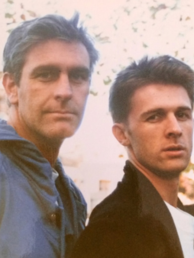 Two men stand together.