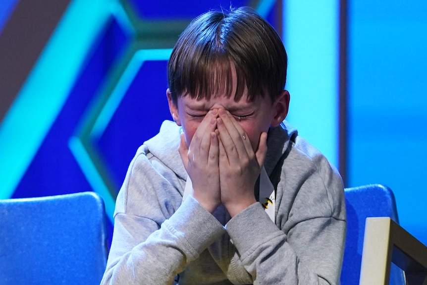 A boy crying with his hands covering his face