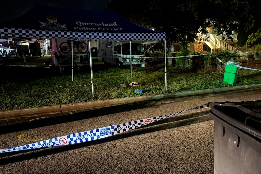 Police tape on a road in front of a police tent.