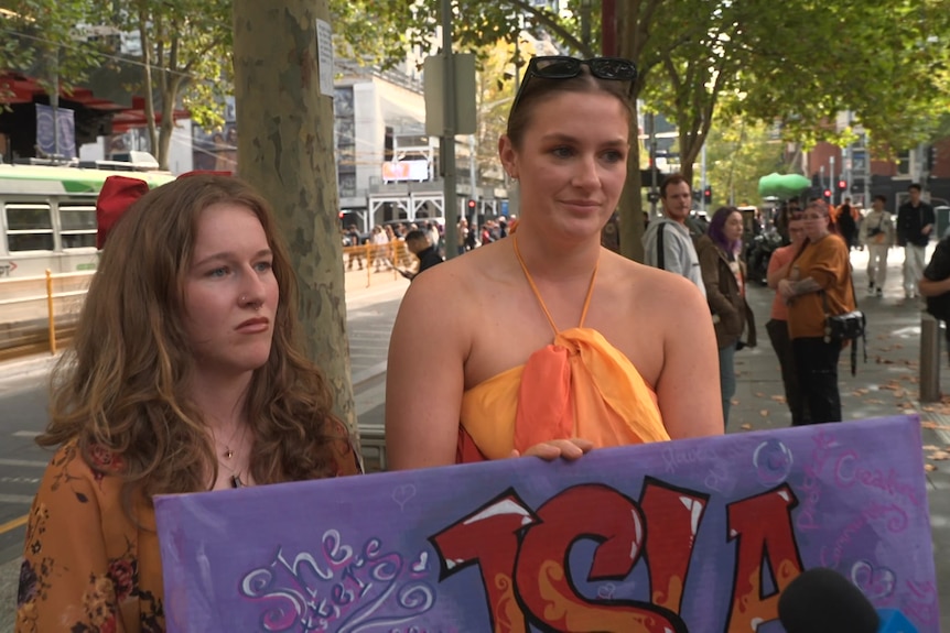 Two women holding a sign for Isla Bell