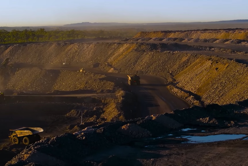 A coal pit in the late afternoon, with barley visible yellow heavy machines.