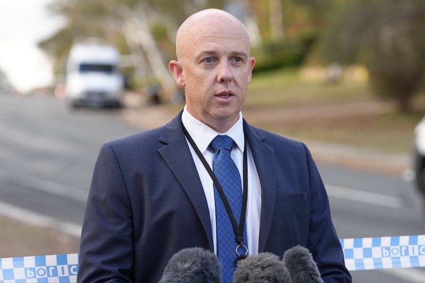 A police officer wearing a blue suit speaks seriously.