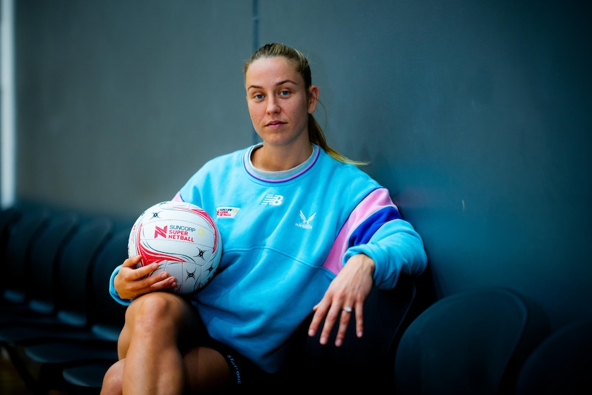 Netballer Jamie-Lee Price holds a netball and stares at the camera.