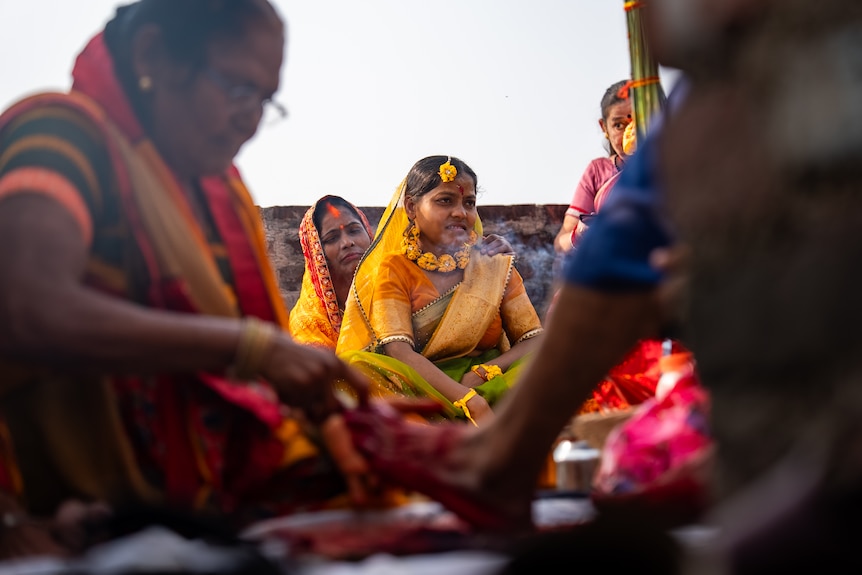 A woman sits with other women.