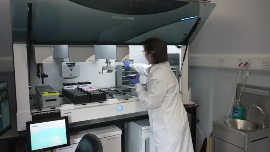 A researcher at the UK Dementia Institute in Edinburgh sets up a machine to test drugs on stem cell cultures