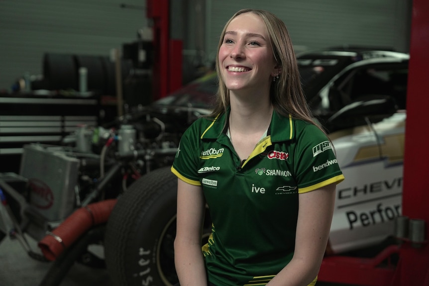 Motorsport enthusiast Alice Buckley sits in a garage on the bonnet of a car