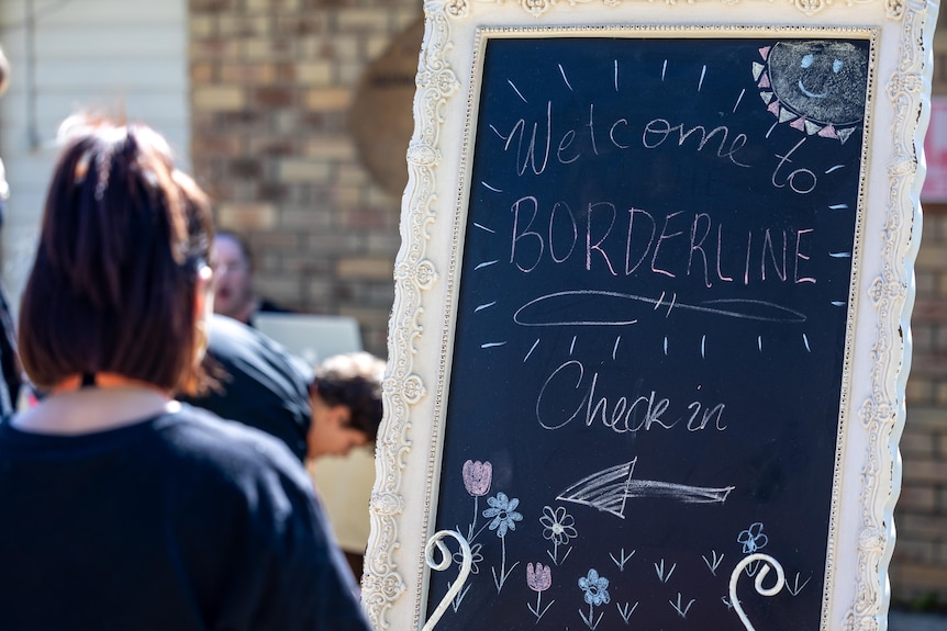 A chalkboard sign that reads 'welcome to borderline, check in'