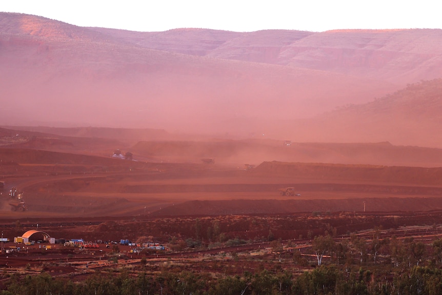 A mine landscape with dust and hills in the background.