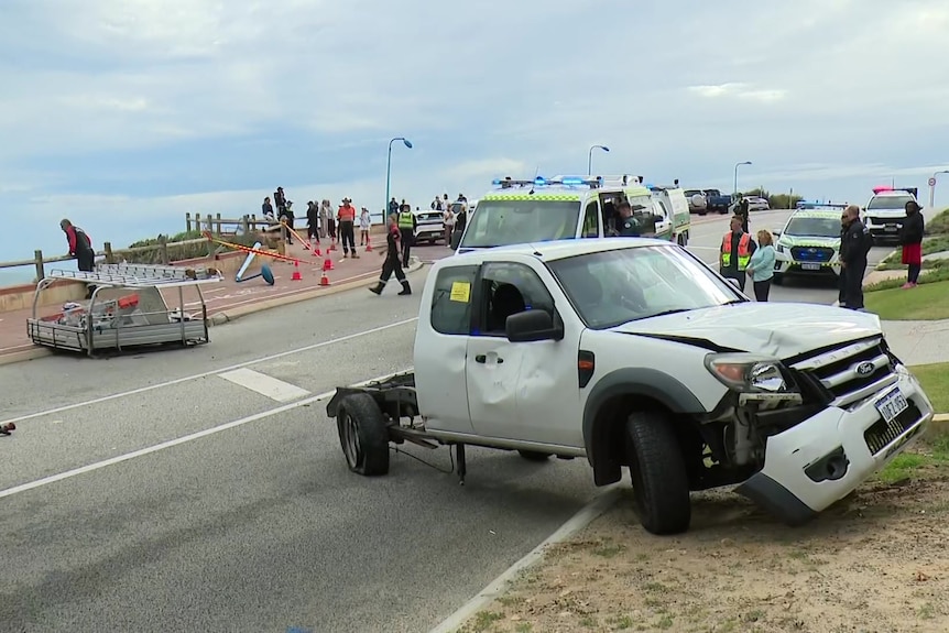 A badly damaged ute with its tray on the road