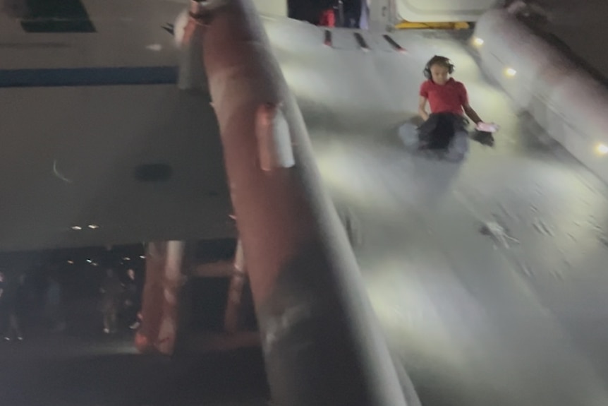 Passengers can be seen exiting a plane using an escape slide at Denver International Airport.