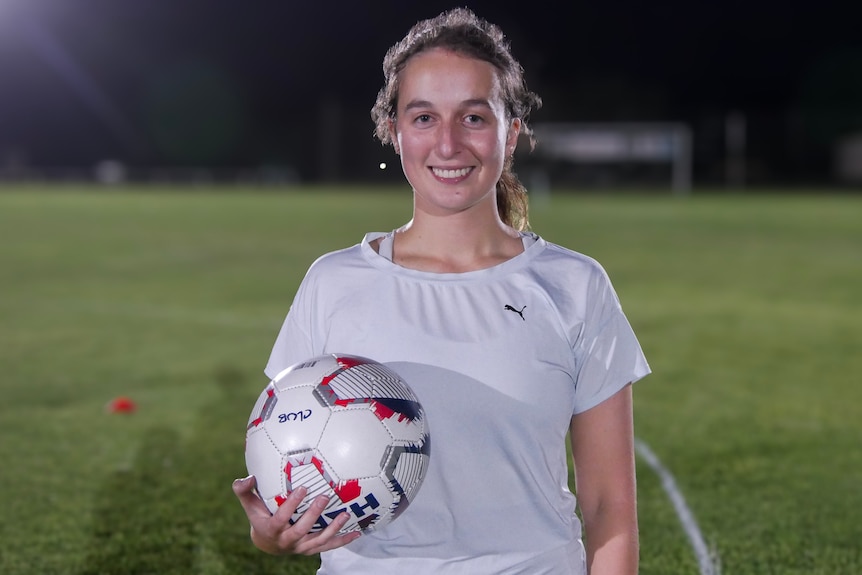 A woman holding a soccer ball.