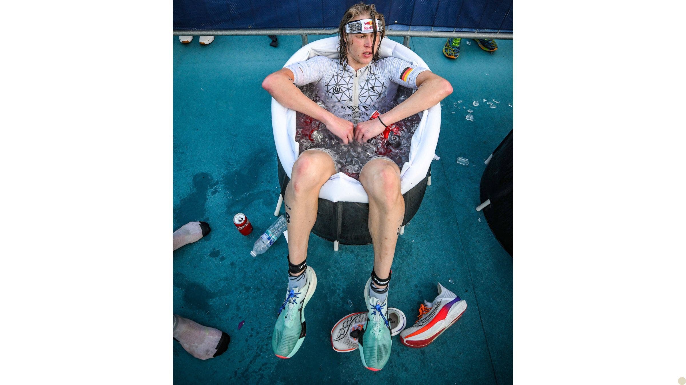 A tired looking athlete sits in a cold plunge tub after a triathlon race.