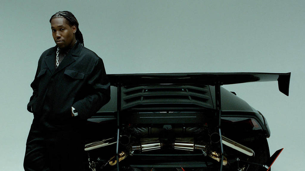 Don Toliver posing next to a sports car