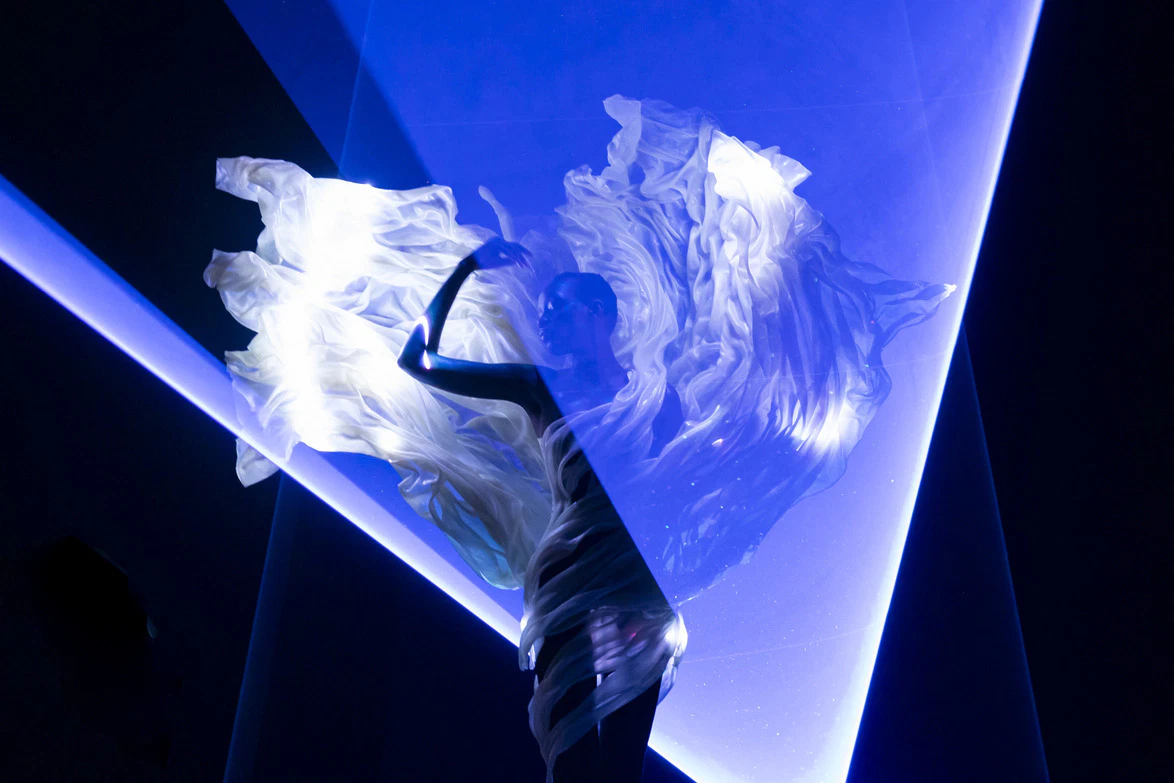 Silhouette of a dancer in flowing fabric and blue light, creating a dynamic and ethereal performance atmosphere.