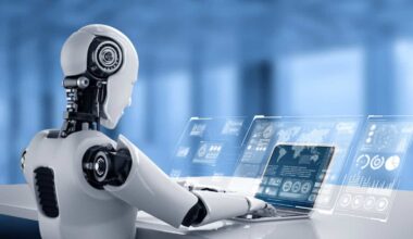 A human-like robot checks out market performance on a laptop, indicating the rise of AI shares.
