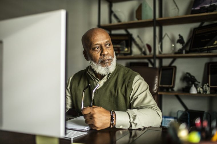 Portrait of senior man at desktop computer in home office - stock photo