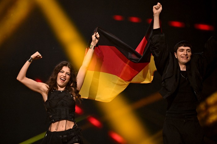 SWITZERLAND-MUSIC-TELEVISION-AWARD-EUROVISION Abor & Tynna walking on stage next to each other, holding up the German flag.