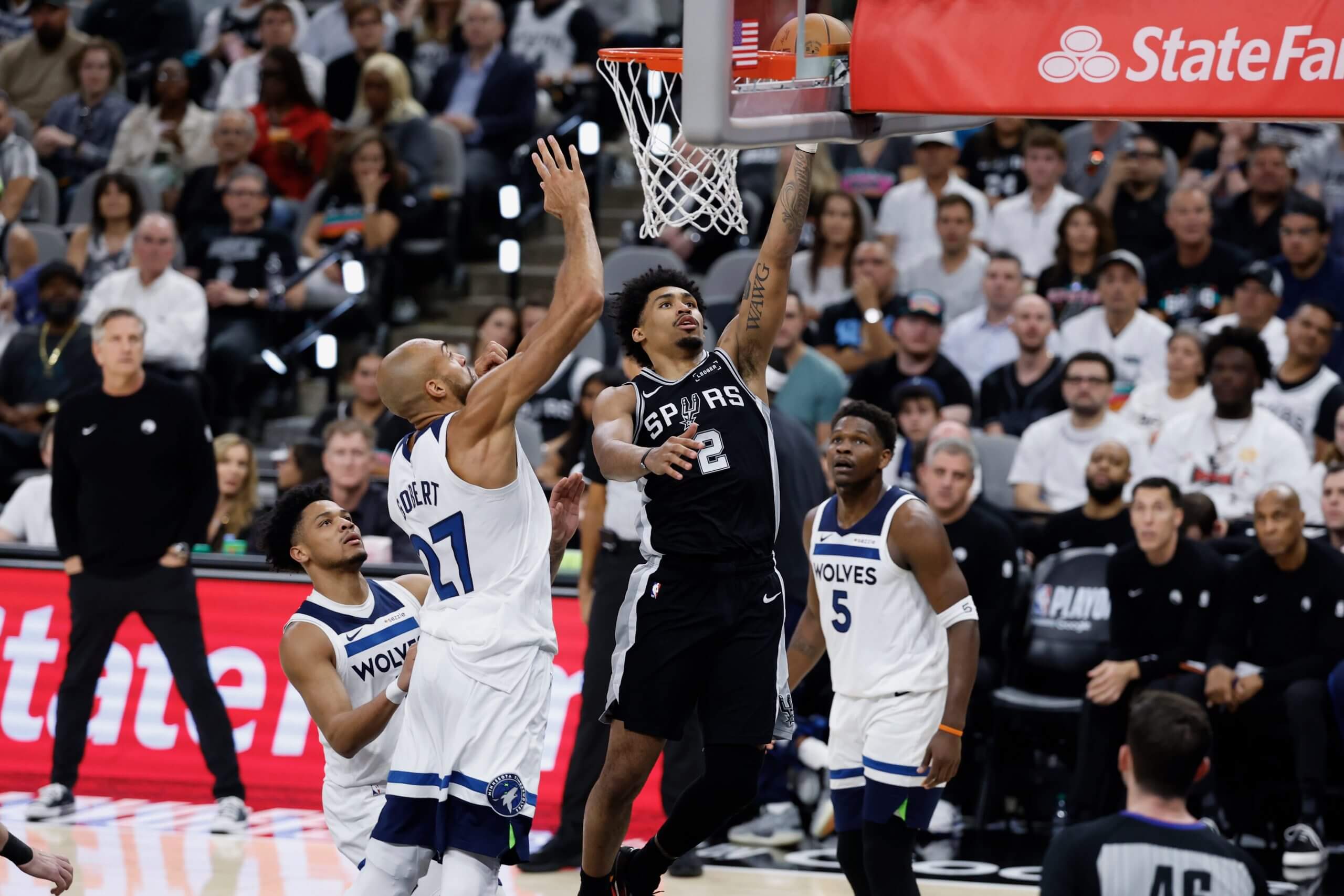 San Antonio Spurs guard Dylan Harper shoots a layup at the rim while Minnesota Timberwolves center Rudy Gobert jumps to challenge the shot during an NBA game.