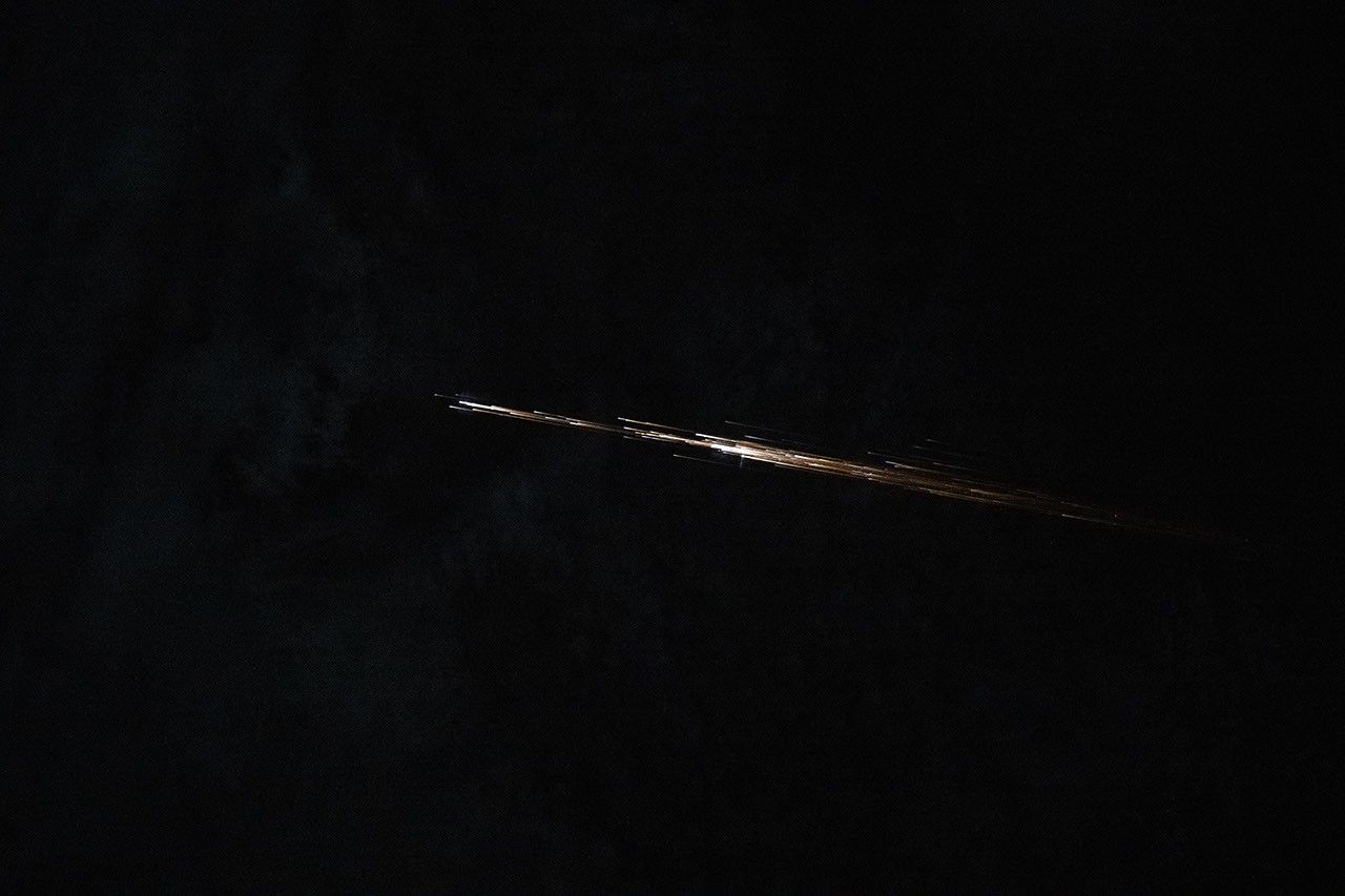 Several long streaks of light are clustered in a line pattern as they streak across a dark background.