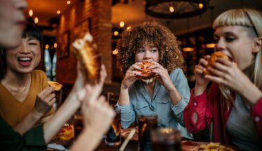 Young happy women eating burgers and talking in a pub