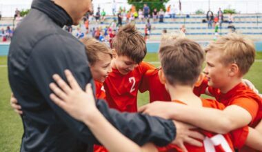 Happy boys in sports team huddling with young coach. Kids standing in a circle on grass sports pitch. Children sports team