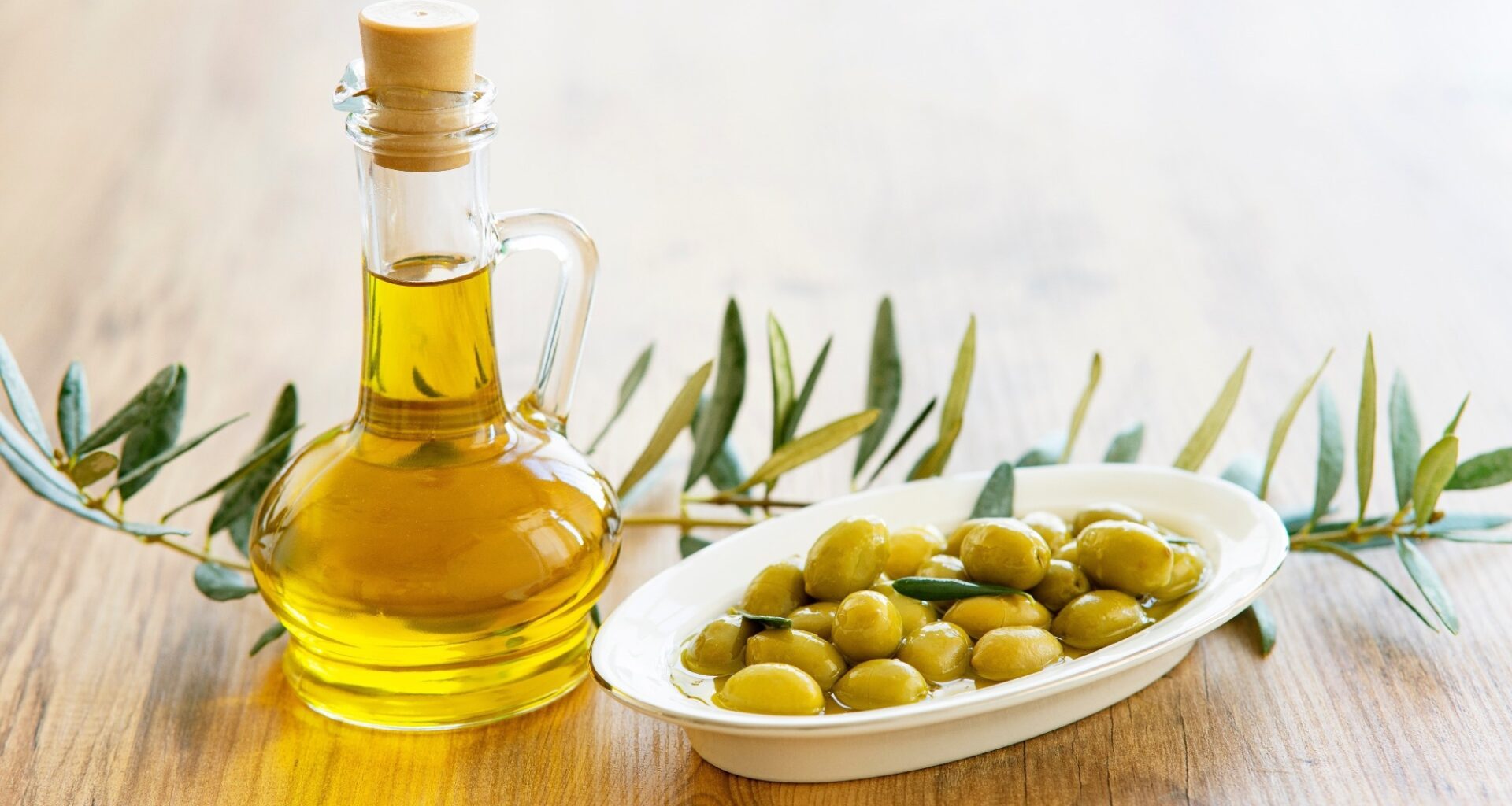 Olive oil and olive berries are on the wooden table