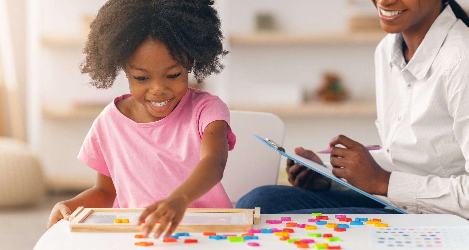 Child Plays With Colorful Shapes While Adult Observes in Bright Indoor Setting