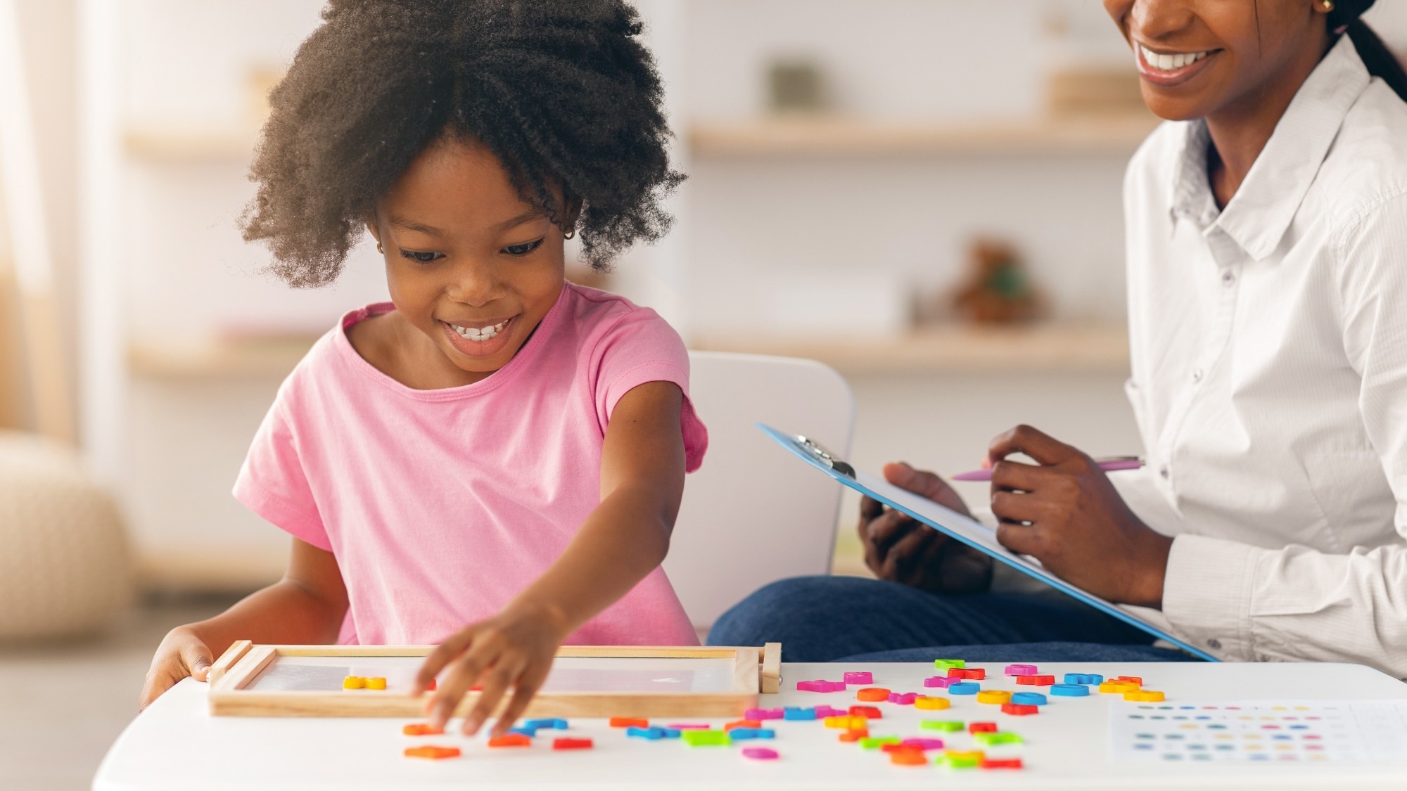 Child Plays With Colorful Shapes While Adult Observes in Bright Indoor Setting