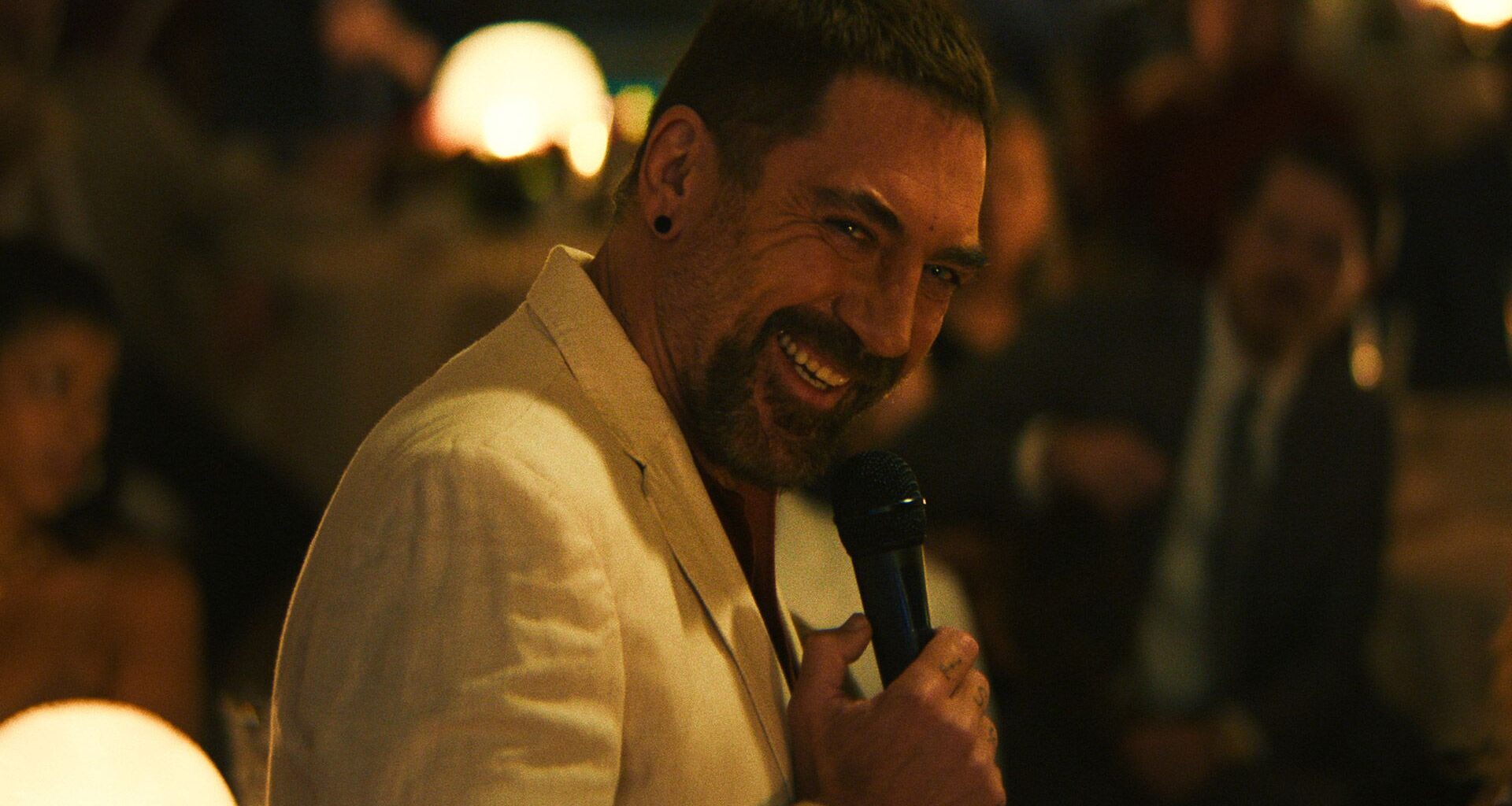 Javier Bardem grins while holding a microphone as Max Cady in Apple TV's Cape Fear remake