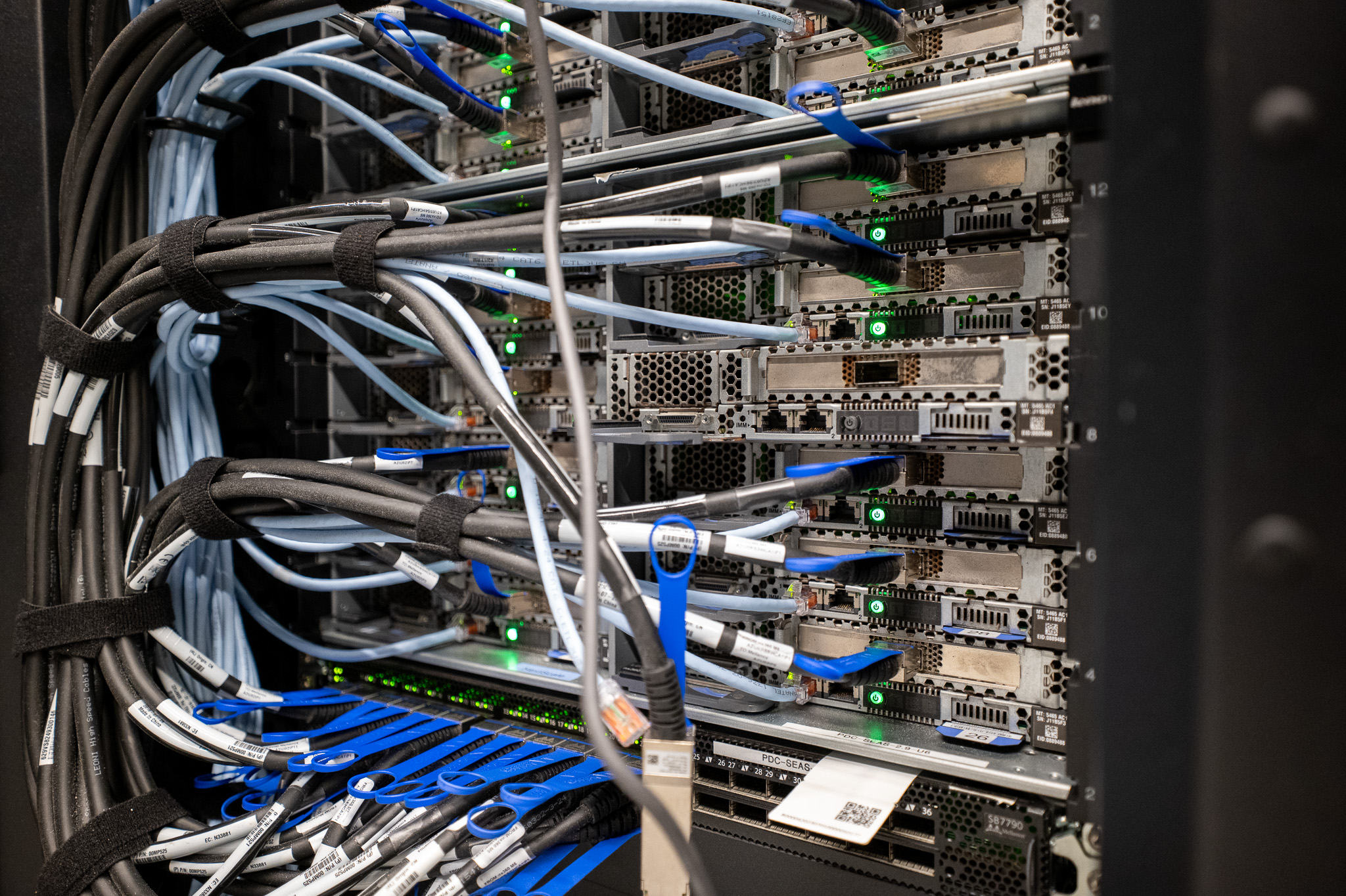 A close-up of wires sticking out of a rack of servers.