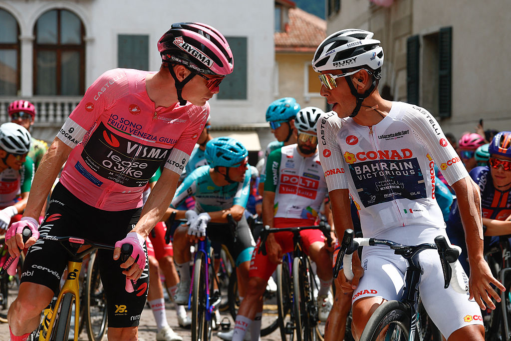 Team Visma Lease a Bike Danish rider Jonas Vingegaard wearing the overall leader's pink jersey (L) speaks with Bahrain - Victorious Portuguese rider Afonso Eulalio wearing the best young rider's white jersey (R) before the start of the 19th stage of the Giro d'Italia 2026 - Tour of Italy cycling race between Feltre and Alleghe, Italy, on May 29, 2026. (Photo by Luca Bettini / AFP)