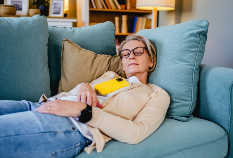 Tired mature woman taking a nap on the sofa in the living room