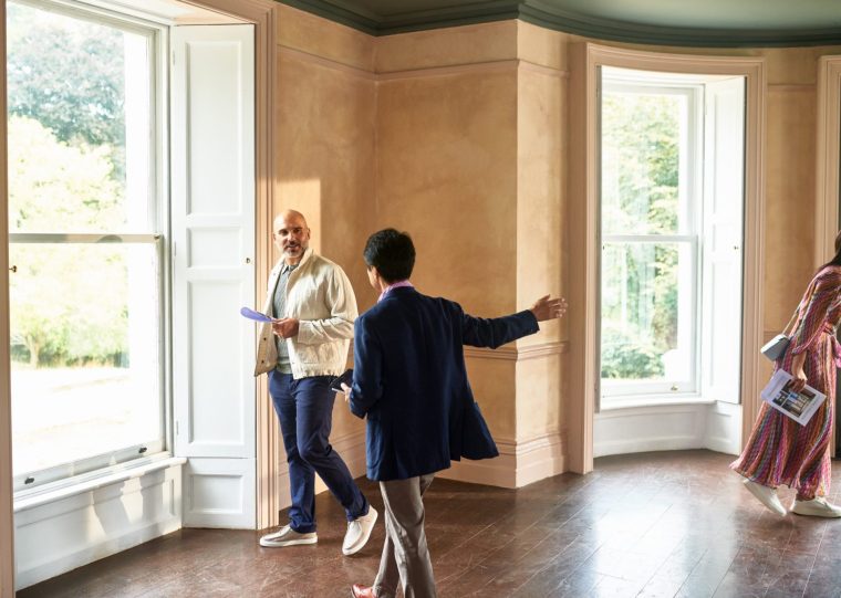 Senior real estate agent showing couple around potential new house pointing out features in spacious empty room, real estate, potential, new life