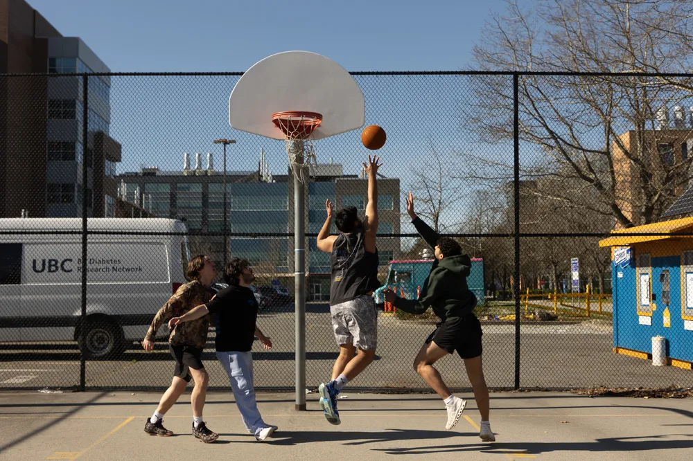 A group of people plays a pick-up game in the courts by the skate park.