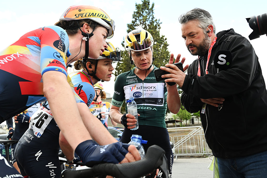 Mischa Bredewold, Anna van der Breggen and Lotte Kopecky watch the sprint on a reporter's phone after Kopecky was relegated