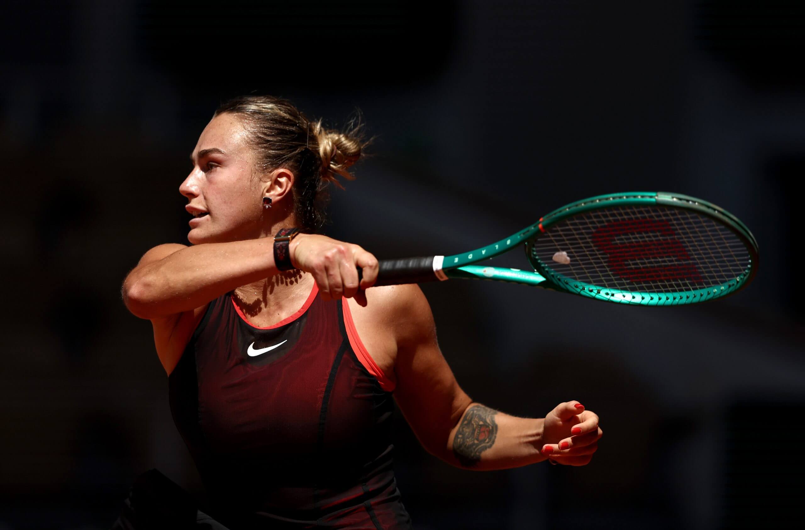 Aryna Sabalenka follows through on a forehand groundstroke with her tennis racket over her left shoulder.