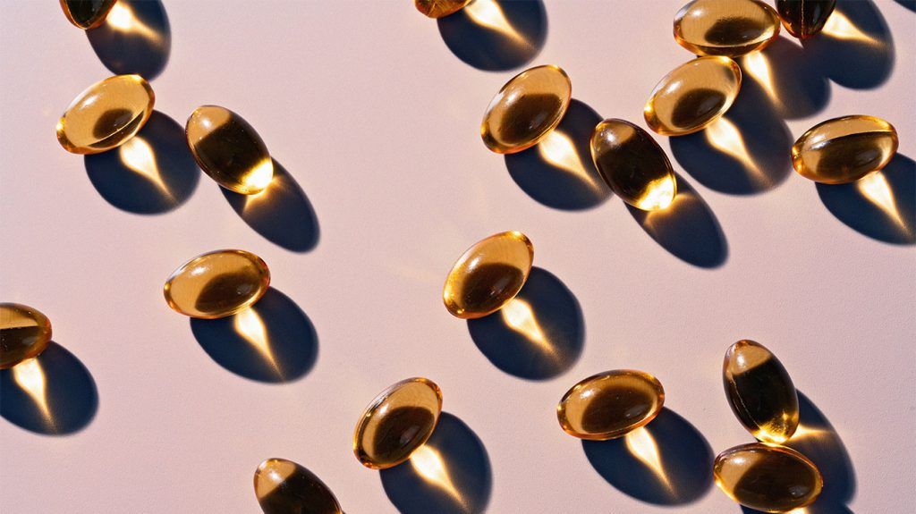 Vitamin D capsules scattered on a flat surface as sunlight creates shadows