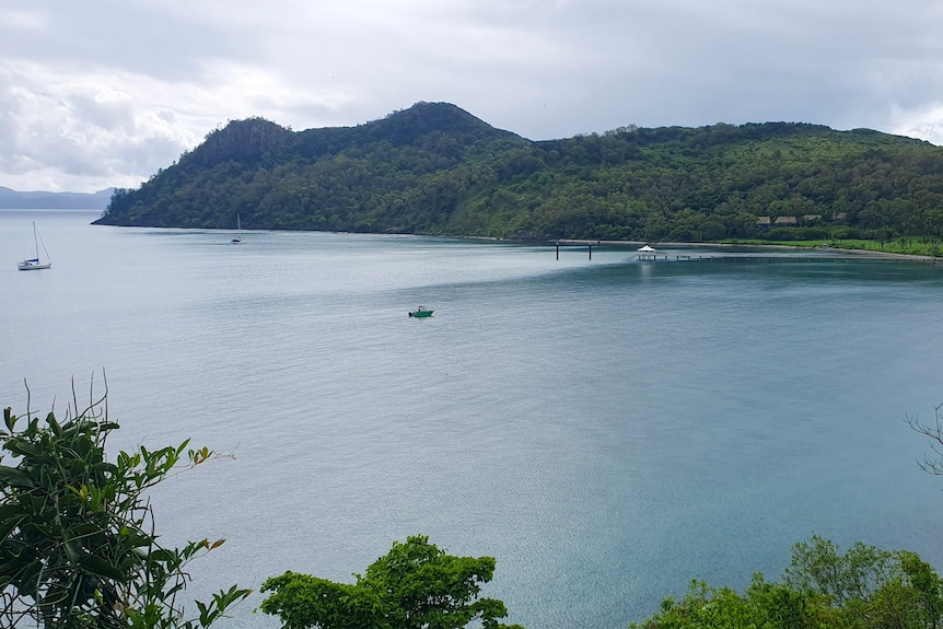 A view of Bauer Bay on South Molle Island, small boats are scattered across the bay, rows of abandoned buildings on the shore
