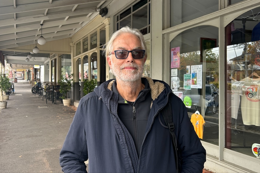 A man with white hair and a beard standing in the high street of Castlemaine