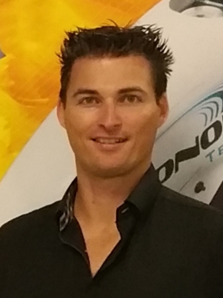 Mr Brown in a black collared shirt smiles at the camera.