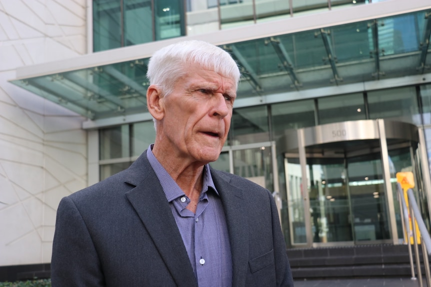 An elderly man speaks to reporters outside court