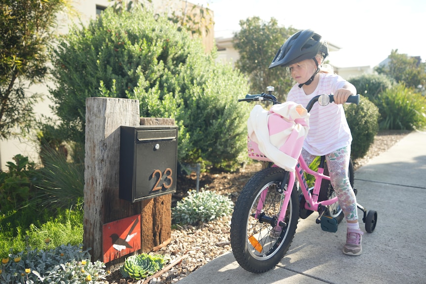Harper, on her bike, sees a red wagtail painting next to a letterbox.