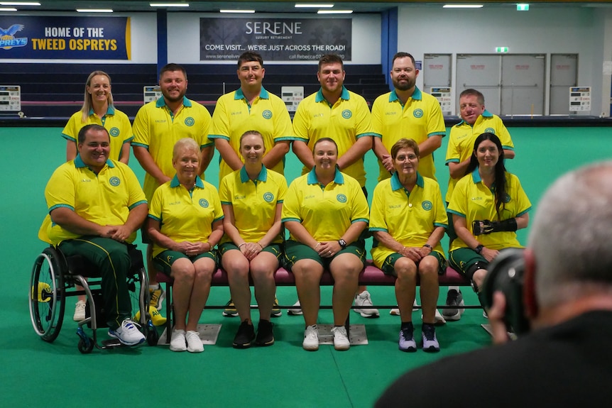 Twelve lawn bowls athletes sit for a team photo