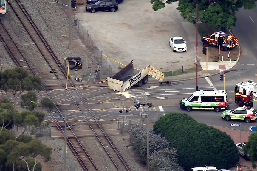 A damaged truck sitting near a train lines.