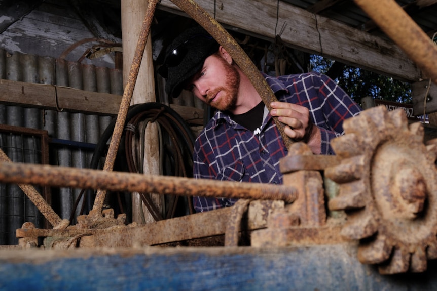 Ned Bott looks into the cider mill wearing a flannelette shirt inside a garage.