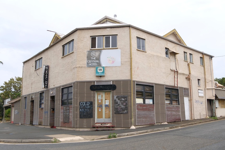 Hotel two storey building, concrete and timber walls, boarded doors and windows, cream colour, road and footpath