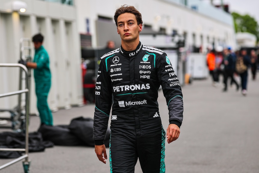 Frustrated F1 driver walking down the pits after retiring from race, wearing race suit, no helmet