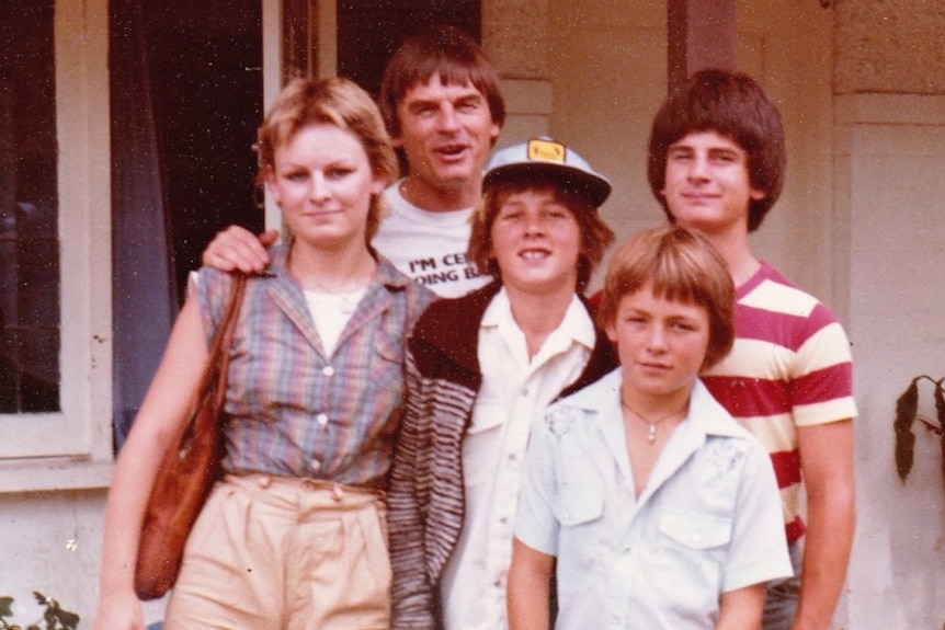 Three boys and a girl with their father in what appears to be early 1980s clothing