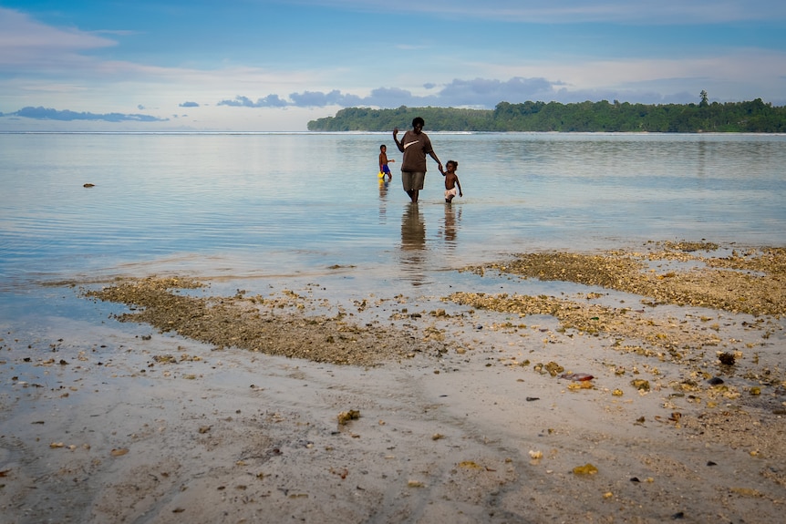 A photo of a beautiful beach with locals walking through the water.
