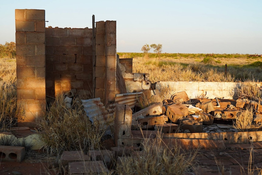 Stone foundations crumble into piles on a grassy plain.